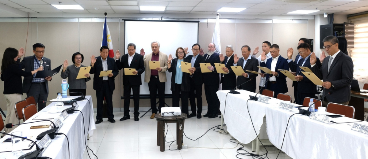Group of professionals standing in a conference room, raising their right hands and holding documents during a formal oath ceremony.