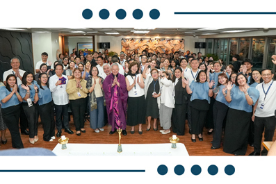 Large diverse group of colleagues posing for a group photo at an indoor event, many smiling and giving thumbs up.