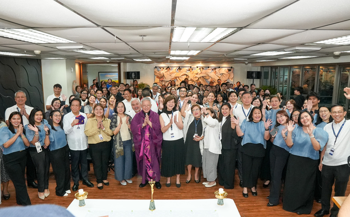 PTC marks 47 years | PTC Large group photo indoors at a faith event; clergy in purple robes center, attendees smile and raise hands, altar in front.