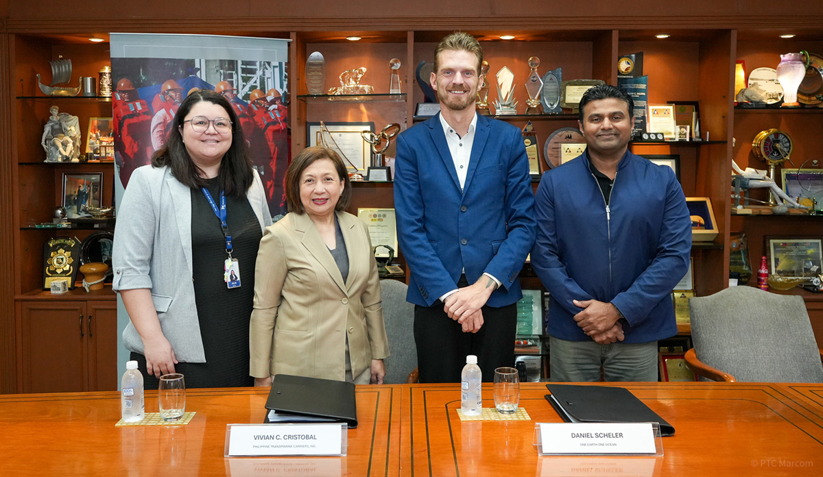Four professionals stand behind a conference table in a trophy-filled office, posing for a group photo.