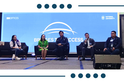 Panel of five speakers seated on a stage during a conference, with a blue backdrop featuring logos and the words 'National University' and 'Business Access' or similar.