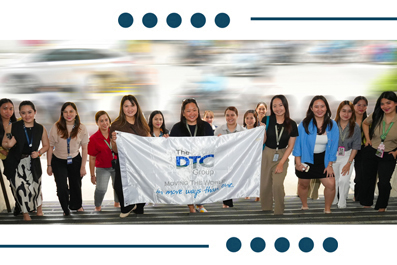 Diverse group of people standing in a line, holding a banner that reads The DTG Group at an event.