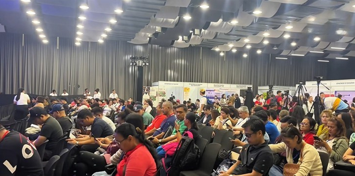 PTC Group joins National Reintegration Network-2 | PTC Large conference hall filled with attendees seated in rows, facing a stage with expo booths in the background. (informative)