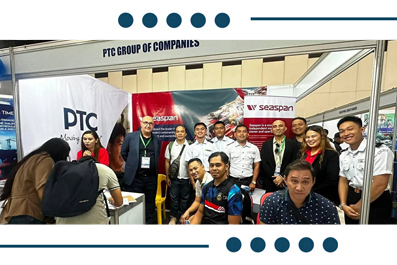 Group photo of diverse professionals posing at a PTC Group of Companies trade show booth with banners in the background.