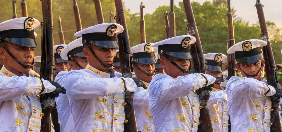 Seafaring dreams take flight-2 | PTC Rows of uniformed soldiers in white dress uniforms holding rifles in a ceremonial drill outdoors, sunlight in the background, synchronized pose.