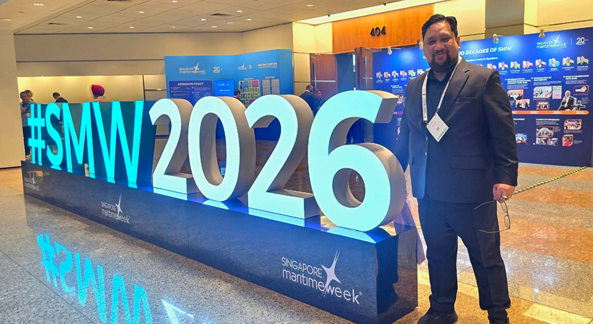 digital transformation at Singapore Maritime Week-2 | PTC Man in a dark suit stands beside a large illuminated #SMW2026 sign at Singapore Maritime Week conference with a lanyard around his neck.
