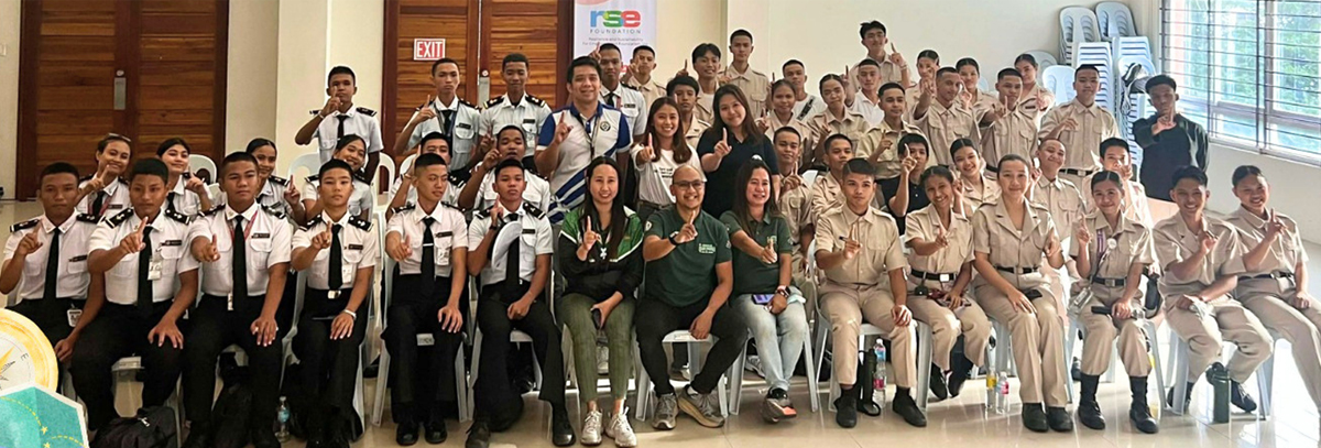 Laguna Senior High School pioneers-2 | PTC Large group of students in white and khaki uniforms posing for a group photo in a bright room, with a few staff in green shirts seated at the front; an RSE Foundation banner is visible in the background.