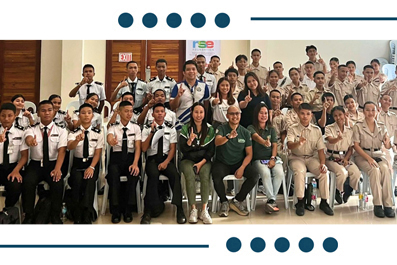 Group photo of students in uniforms and staff posing together in a training hall or classroom setting.