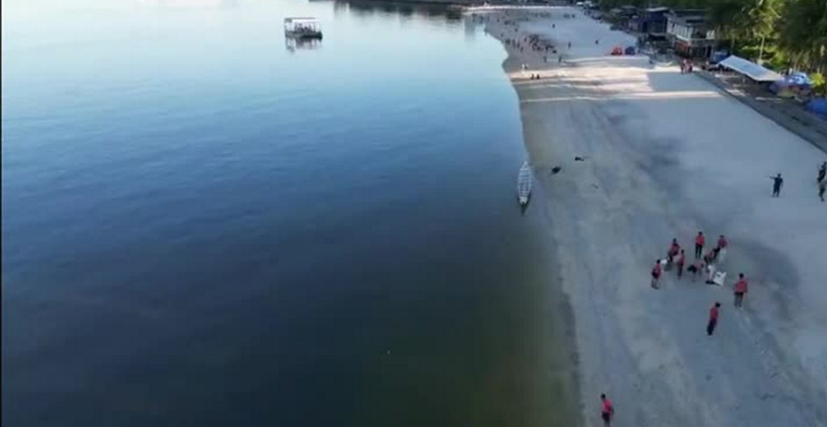 One Earth One Ocean and PTC advance marine-3 | PTC Aerial view of a calm shoreline with a small group of people in red shirts on the sandy beach beside a boat by the water edge.