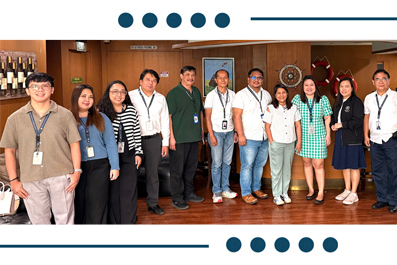 Twelve diverse professionals posing in a wood-paneled room, many wearing lanyards and name badges for a group photo.