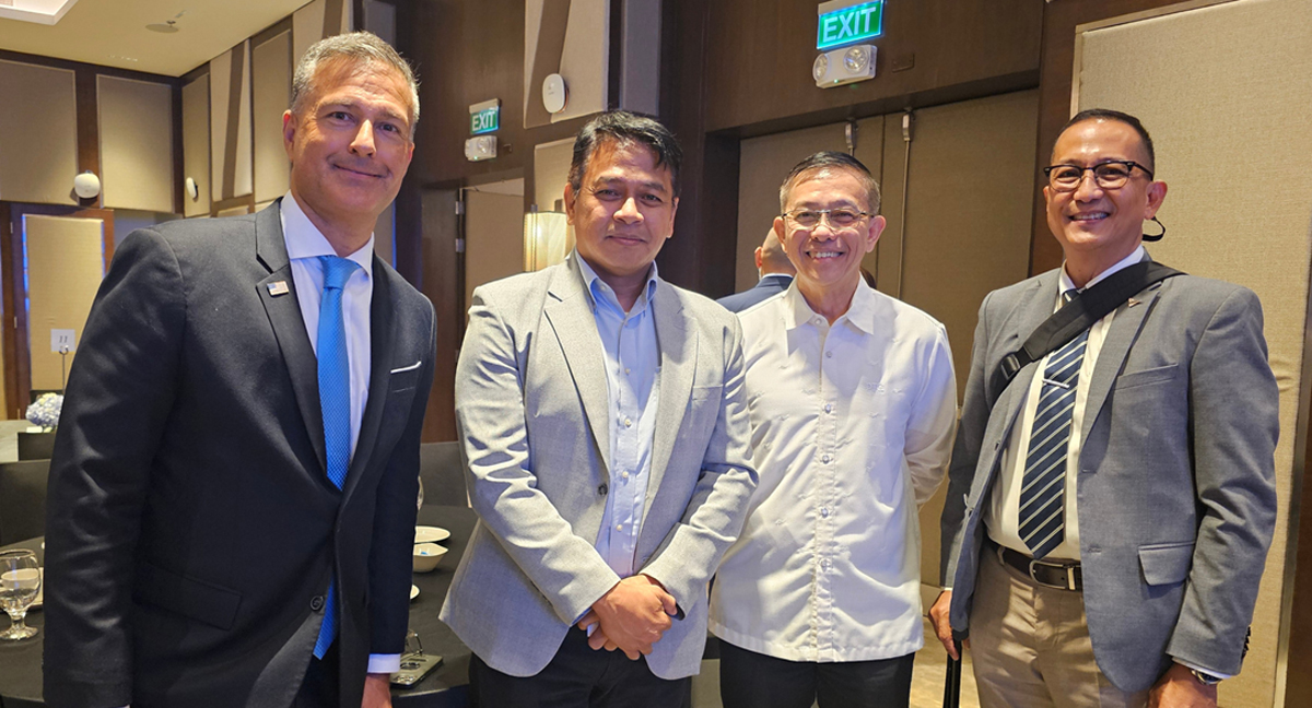 Padilla outlines Ph prospects-3 | PTC Four businesspeople posing for a group photo at a formal event, all in suits, in a banquet-style room with tables in the background.