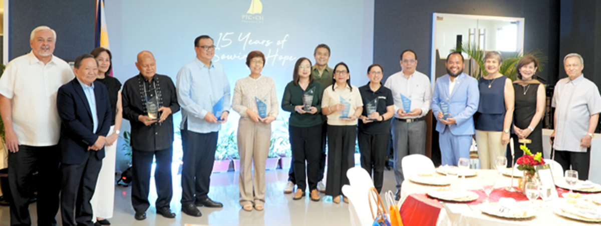 A diverse group of professionals posing with awards at a ceremony, standing in a row in a conference room with a blue backdrop.