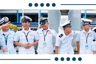 Group of five naval officers in white uniforms with lanyards, standing outdoors and chatting, smiling at each other.