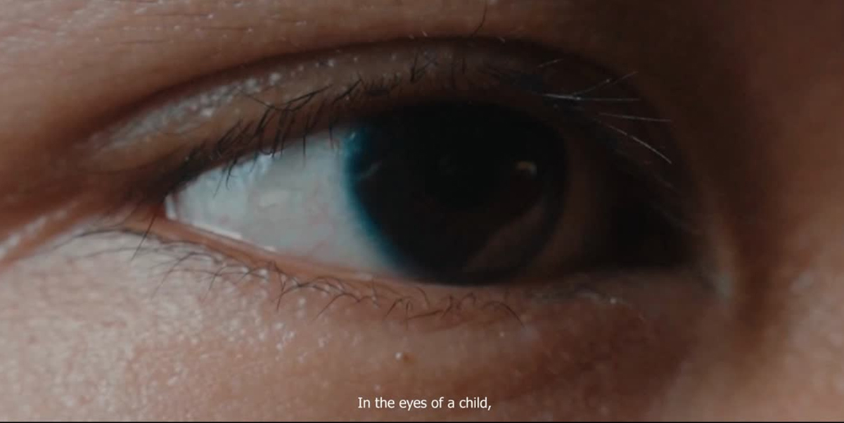 Close-up of a child’s eye showing the dark iris and lashes; caption reads 'In the eyes of a child,'