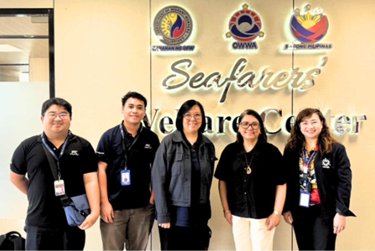 Five staff members wearing badges stand in front of a wall with the 'Seafarers Welcome Center' sign and maritime logos.