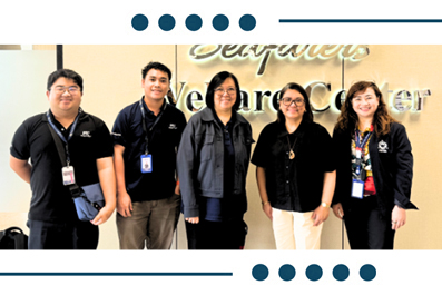 Five staff members wearing badges stand together in front of a Wellness Center sign.