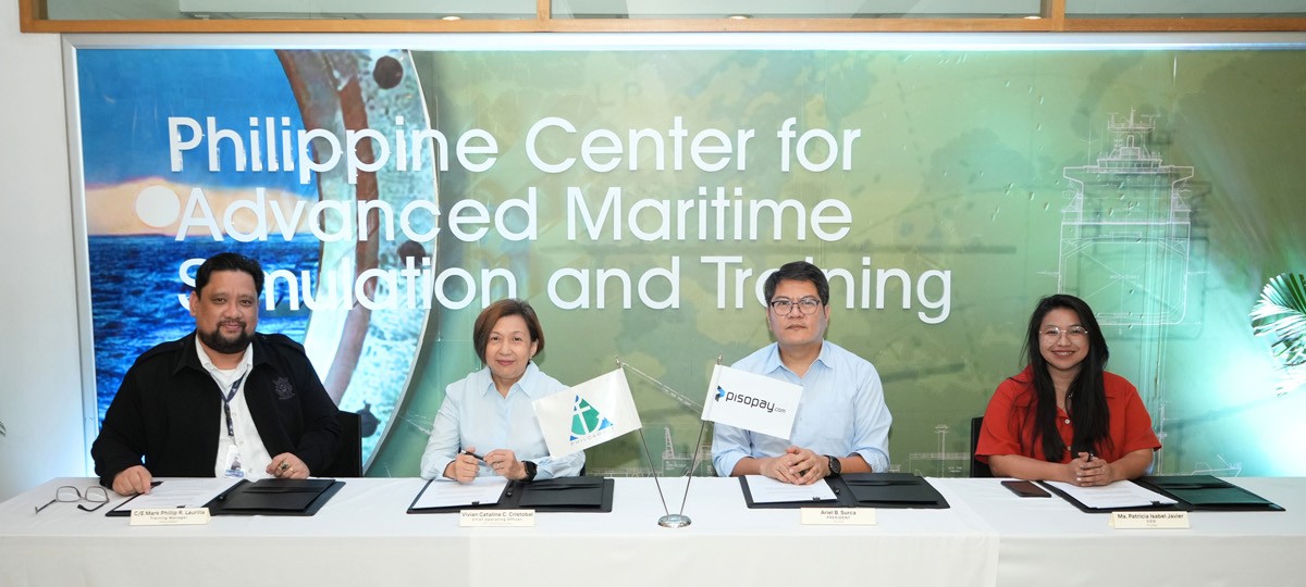 PHILCAMSAT partners with PisoPay 02 | PTC Four professionals sign documents at a formal ceremony, seated at a white table with small flags and nameplates, in front of a banner that reads 'Philippine Center for Advanced Maritime Simulation and Training'.