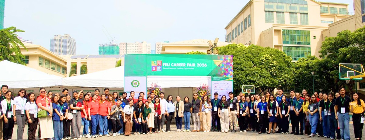 PTC TAG participates in FEU Career 02 | PTC Diverse group of people with lanyards posing outdoors at a campus career fair in front of a banner that reads FEU Career Fair 2026