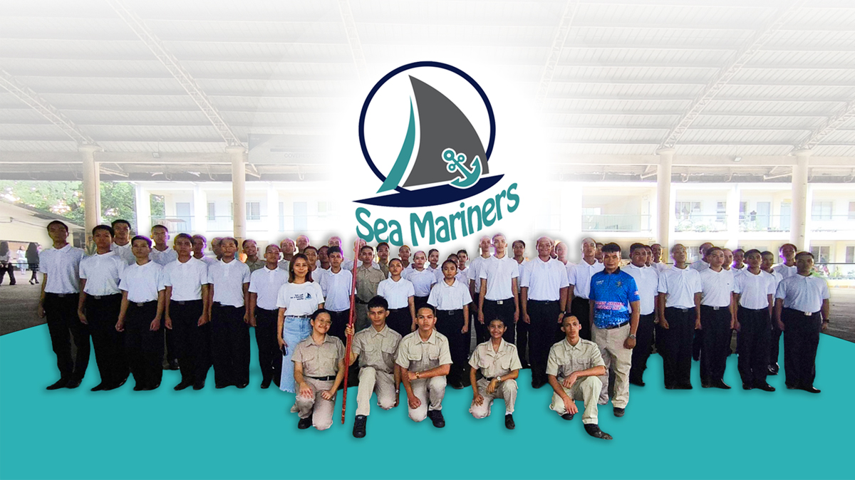 Group photo of Sea Mariners cadets and instructors in uniform, with the Sea Mariners logo above them in a bright, indoor venue.