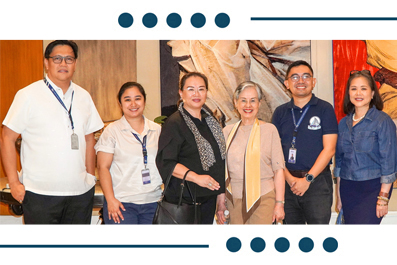 Six diverse professionals stand in a row, wearing ID badges, posing for a group photo in front of artwork.